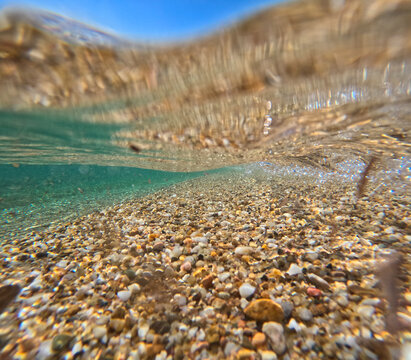 Underwater action shot of glass clear turquoise water and waves split on the lens between sky and wave in Greece