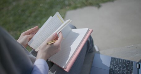 A close-up shot of a hand-held girl holding a pen and leafing through a notebook with handwritten notes. © Anatoly Repin