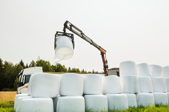 Crane stacking hay bales while working in field