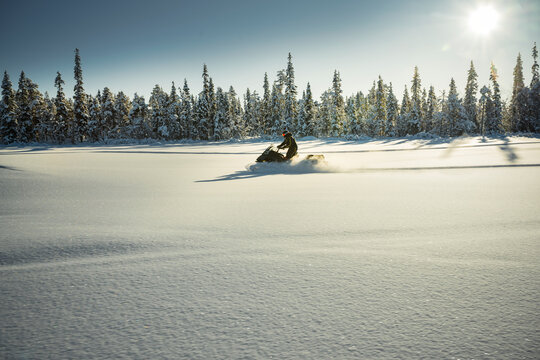 Distant shot of person riding snowmobile on beautiful snowy plain