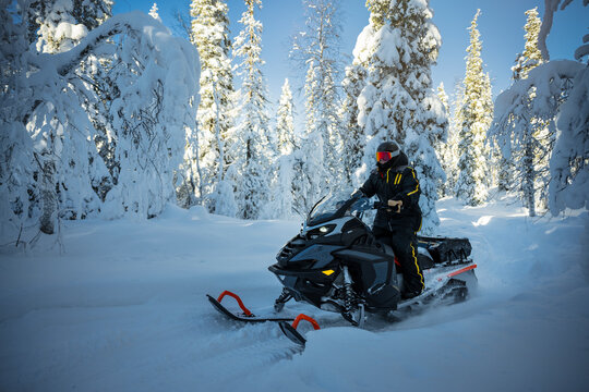 Shot of rider exploring snowy forest on snowmobile