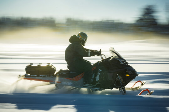 Motion shot of person driving snowmobile on snowy field