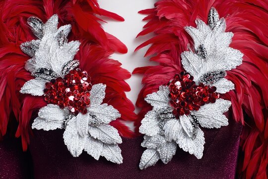 Ornate white floral sequin embroidery on rich burgundy fabric background with elegant texture