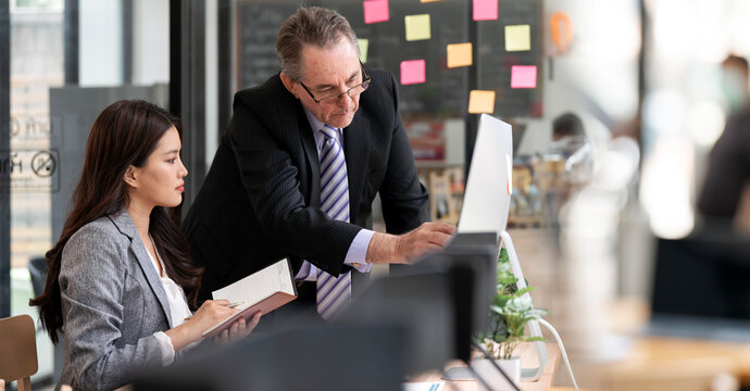 Senior Businessman Explaining Financial Report to Young Colleague