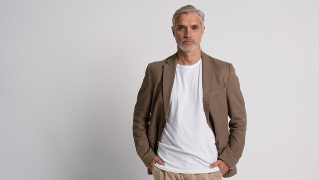 Serious middle-aged man posing in front of a grey background with copy space.