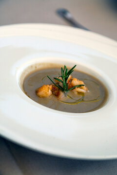 Close-up of creamy mushroom soup garnished with sprig of rosemary