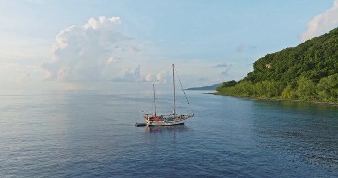 Torres Islands, Vanuatu travel. Sailboat anchored in calm blue waters off lush tropical island, peaceful seascape evoking serene adventure, remote paradise and tranquil summer escape drone panorama