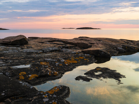 Reflection of clouds seen in tidal pool by rocky shore at dusk