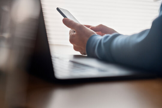 Freelancer using smart phone while sitting at desk