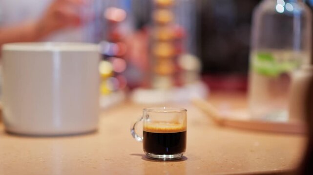 Small glass of espresso coffee with crema on a counter top, close up shot.