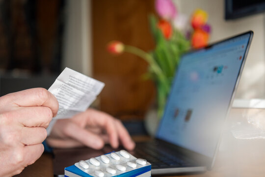 Close-up of man reading prescription before taking medicines at home