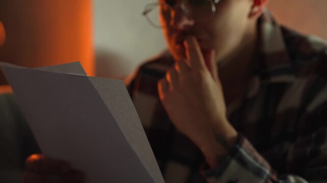 A student wearing glasses in a dark room prepares for exams and studies material for successful university admission.