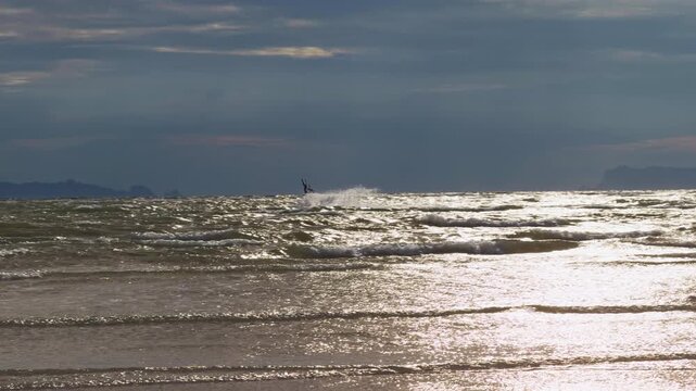 Silhouette of Kitesurfer Jumping Above Ocean Waves Under Dramatic Evening Sky Near Tropical Islands, Slow Motion Extreme Water Sport