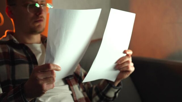 A student wearing glasses in a dark room prepares for exams and studies material for successful university admission.