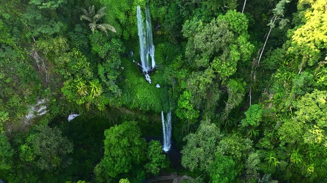 Aerial view of Sendang Gile Waterfall cascading through dense tropical jungle and lush green foliage in Kecamatan Bayan, Nusa Tenggara Barat, Indonesia.