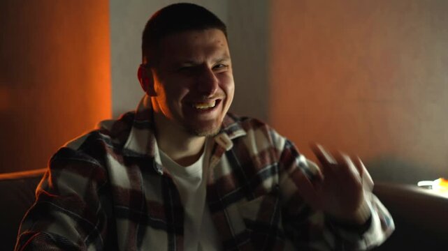 A young man in a plaid shirt smiles and shyly waves his arms.
A hearty laugh at a very funny joke.