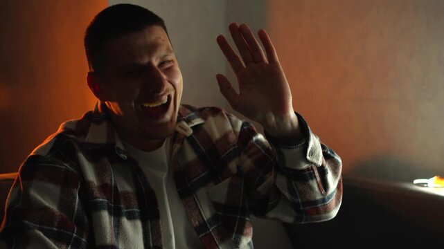 A man laughs heartily in a dark room.
A happy man with a smile on his face
