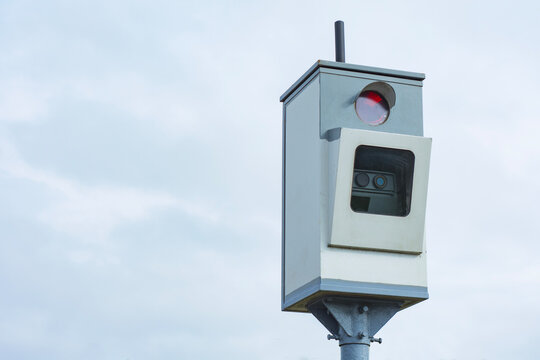Speed camera on pole against cloudy sky background. Traffic enforcement radar, automated speed control device, highway security system or transport safety concept with copy space.