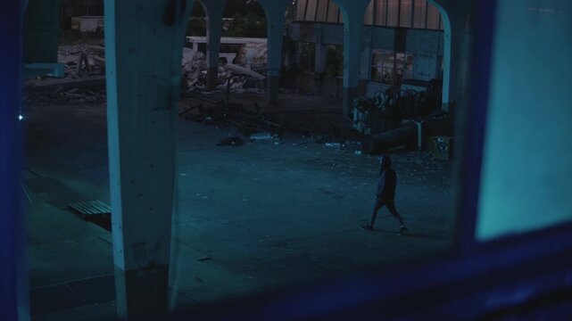 Dangerous Hooded Man is walking through the abandoned factory. Hideout Place has Dark Atmosphere. Shot on Arri Alexa Mini Camera.