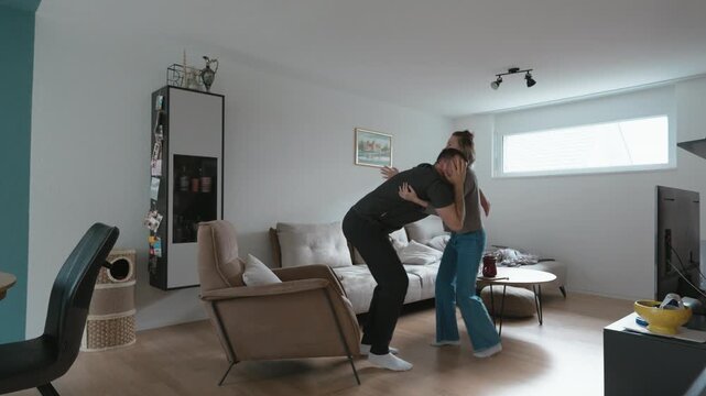 A woman supports a dizzy man as he loses balance while standing in a modern living room, showing care, health concern, assistance, weakness, and emergency support at home.
