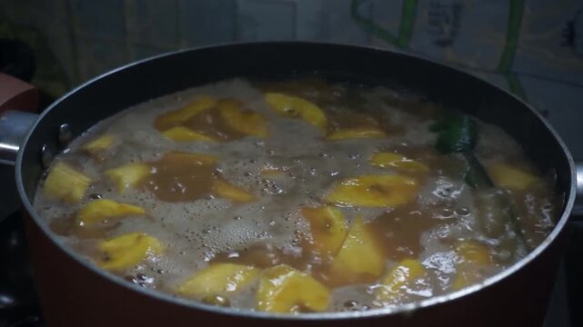 Boiling sweet banana soup or kolak pisang with coconut milk and palm sugar in a cooking pot