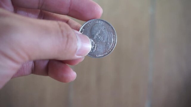 Close-up of human hand holding and showing Indonesian 500 Rupiah coin featuring Lieutenant General T.B. Simatupang and nominal value, concept of finance, economy, and Indonesian currency.