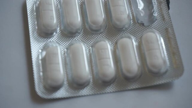 Close-up of a medicine blister pack with white tablet pills and one empty slot, concept of medical treatment, healthcare, pharmacy, and daily dosage.