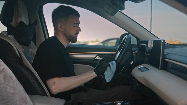 Man is cleaning the leather steering wheel in his car. Close-up of the interior, showing the thorough cleaning of the steering wheel