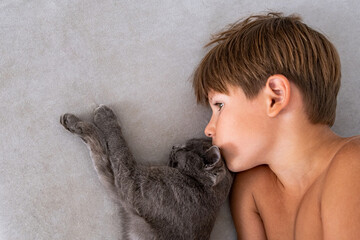 Tender Moment Between a Child and a Gray Cat, Close-Up of Affection A delightful image of a smiling boy and a gray cat gazing into each other’s eyes, capturing a playful and heartwarming moment.  © Irina