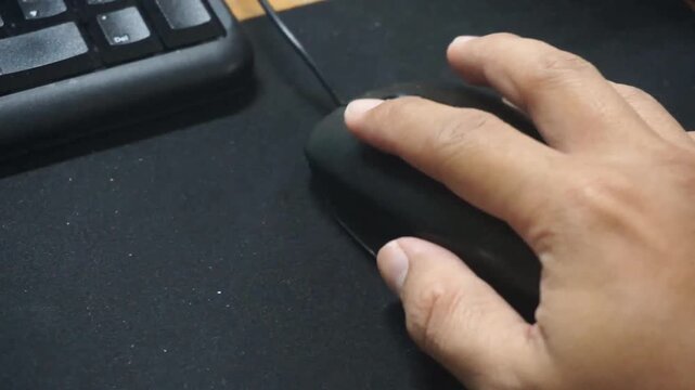 Close-up of a man's hand using and clicking a computer mouse on a desk. Office worker concept.