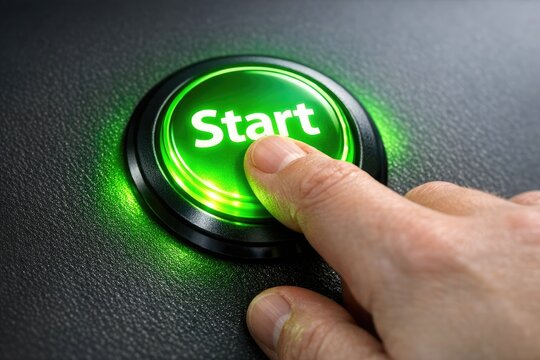 A person's hand pressing a green start button, a common gesture in various contexts