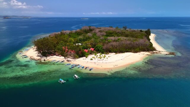 Aerial view of Gili Nanggu island featuring white sandy beaches, turquoise waters, and traditional outrigger boats anchored on the shore in Sekotong, West Nusa Tenggara, Indonesia.