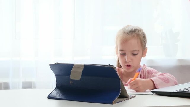 Hybrid learning child studying at desk with laptop and notebook