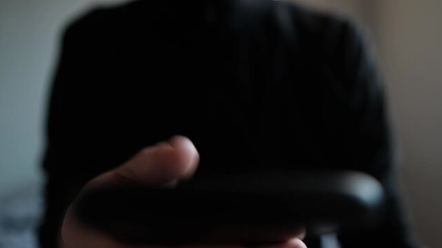 Closeup hands holding phone daytime scroll feed, soft natural light silhouette torso, repeated thumb swipes, distracted routine and subtle tension, habitual