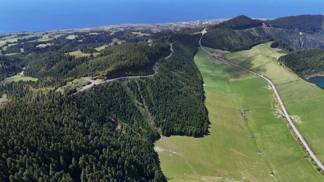 Aerial drone flight over the lush green ridges and forests of Sete Cidades on Sao Miguel Island, Azores. Stunning panoramic view of the volcanic landscape and the deep blue Atlantic horizon