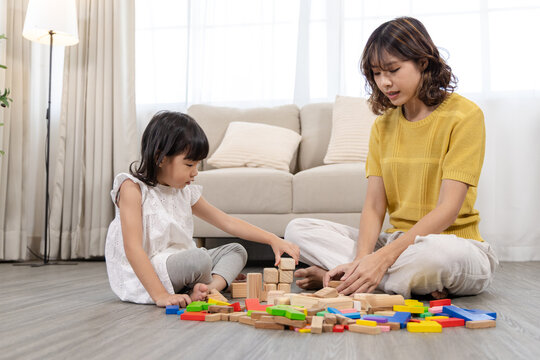 Happy children play and learn, education, homeschool little girl create wooden toy block build the house, improving intelligence and knowledge with mother, supporting emotional quotient creativity