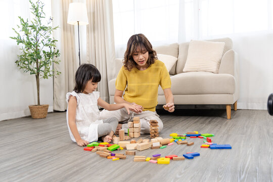 Happy children play and learn, education, homeschool little girl create wooden toy block build the house, improving intelligence and knowledge with mother, supporting emotional quotient creativity