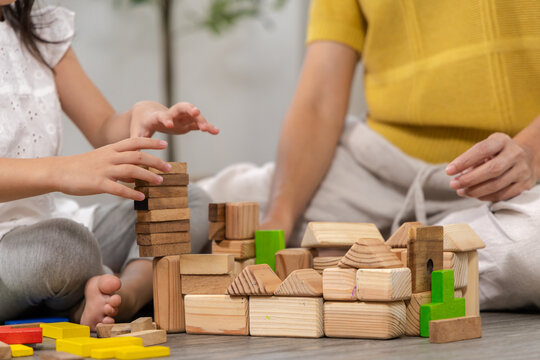 Happy children play and learn, education, homeschool little girl create wooden toy block build the house, improving intelligence and knowledge with mother, supporting emotional quotient creativity