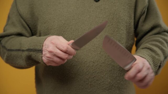 Man sharpening a chef knife against another knife, blade sharpening action with motion blur.