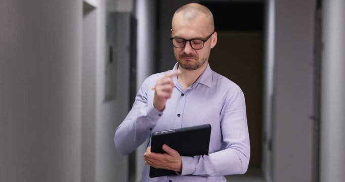 Organized bald engineer writes technical details into formal document as inspects various areas of building. Businessman records precise observations into report