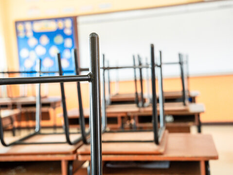 School classroom in blur background without young student. Blurry view of elementary class room no kid or teacher with chairs and tables in campus. Back to school concept