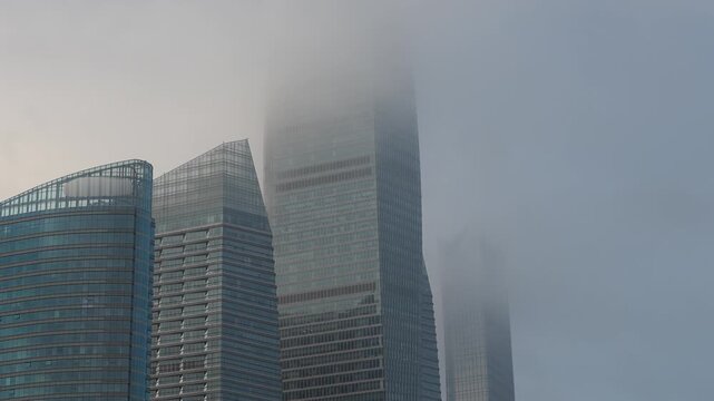 This shot captures modern high-rise buildings partially obscured by thick fog and haze in an urban downtown area.