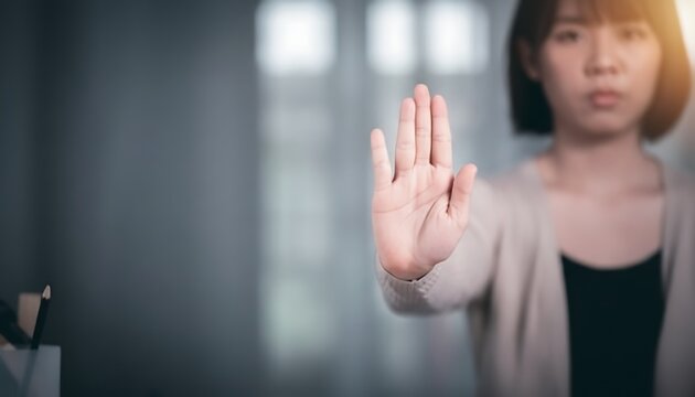 Serious young woman showing a stop hand gesture with palm out, indicating refusal or prohibition.