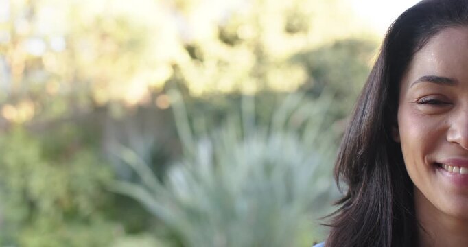 Woman hearing laugh, smiling and laughing in sunny garden by spiky plant, copy space