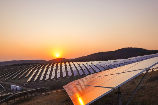 Solar Panels Reflecting Golden Sunset Over Rolling Hills