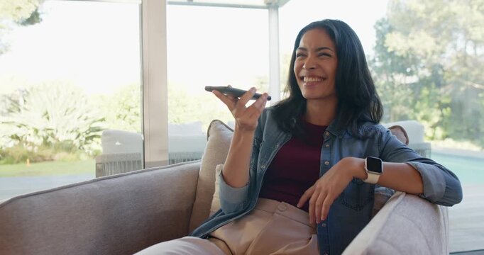 African American woman raising smartphone to speak, recording voice message and laughing on sofa