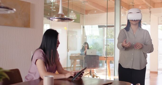 Diverse female team watching African-American woman placing VR headset demoing at table, copy space