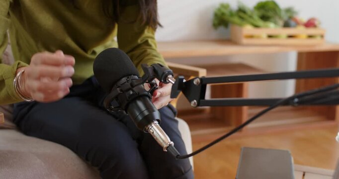 African American woman connecting microphone and XLR cable at home, preparing to record on laptop