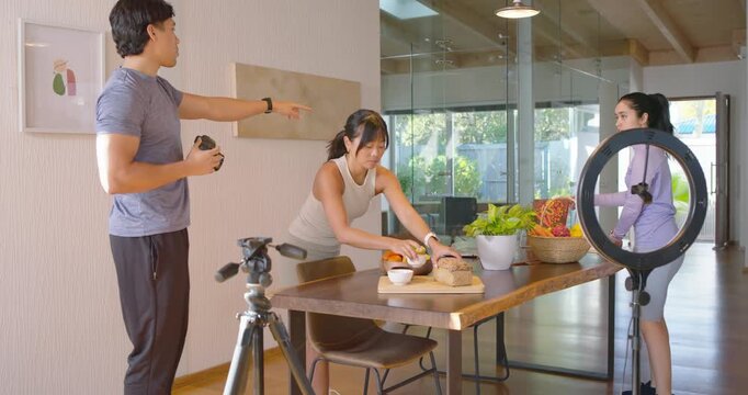 Diverse team reacting to photographer placing DSLR on tripod, arranging bowls for shoot at table
