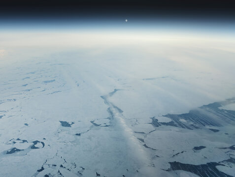 Aerial view of icy expanses reflect the ethereal glow of the horizon, a stark contrast against the deep blue of the sky, Narsarsuaq, Greenland.